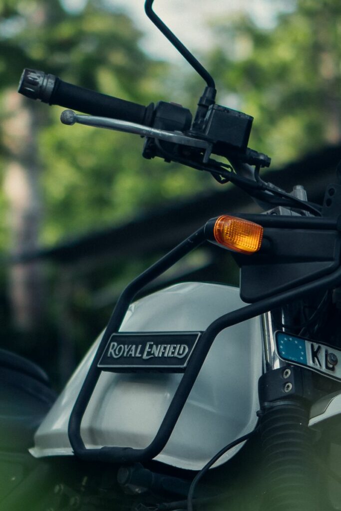 Close-up of a Royal Enfield motorcycle in a green outdoor Kerala landscape.