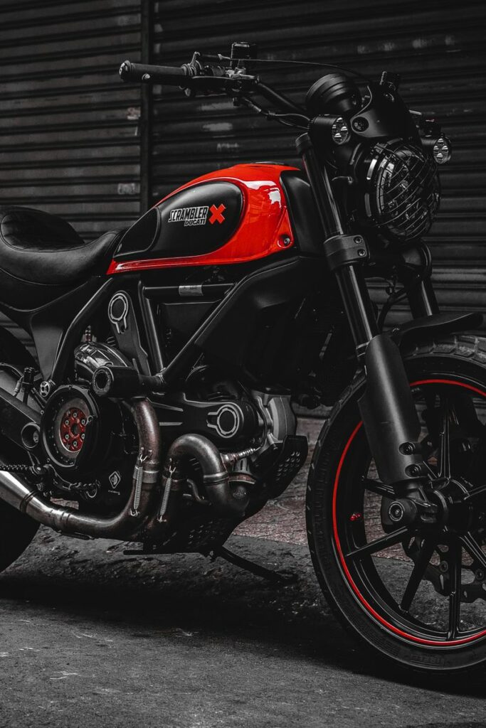 A stylish black and red Ducati Scrambler motorcycle parked on a city street, showcasing its robust design.